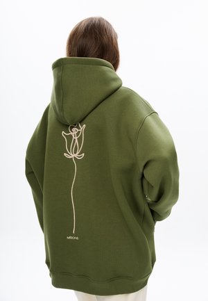 Olijfgroene hoodie met een grote rozenborduursel in lichtbeige op de rug. Zachte textuur, oversized pasvorm en ribgebreide manchetten en zoom.
