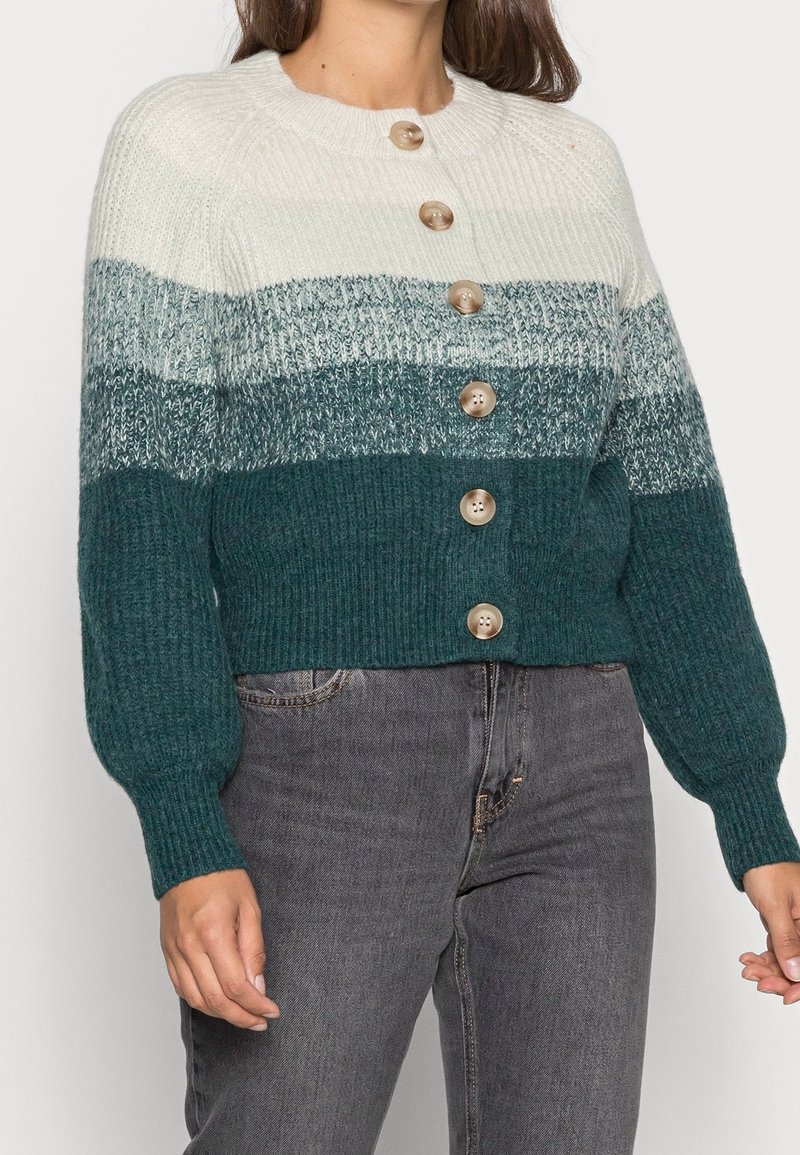 Cardigan en maille présentant un dégradé de couleurs crème, bleu sarcelle et vert foncé. Fini avec cinq grands boutons et des poignets côtelés.
