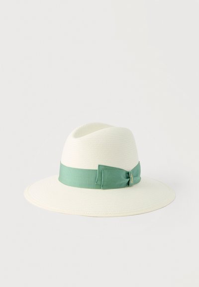 Λευκό φαρδύ καπέλο φεντόρα με πράσινη υφασμάτινη ταινία και λεπτομέρεια φιόγκου σε απλό ανοιχτό φόντο.