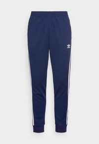 Tmavě modré teplákové kalhoty z měkké látky s bílými pruhy po stranách, elastickým pasem a žebrovanými manžetami u kotníků. Malé logo na boku.