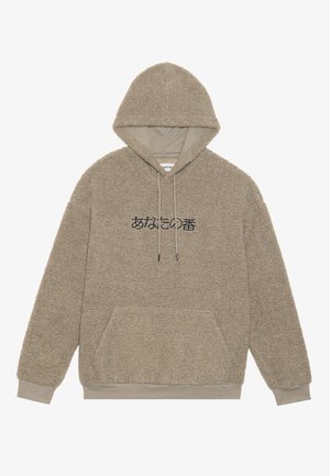 Beige Kapuzenpullover aus einem strukturierten, flauschigen Material. Verfügt über eine Kängurutasche und schwarzen japanischen Text auf der Vorderseite.