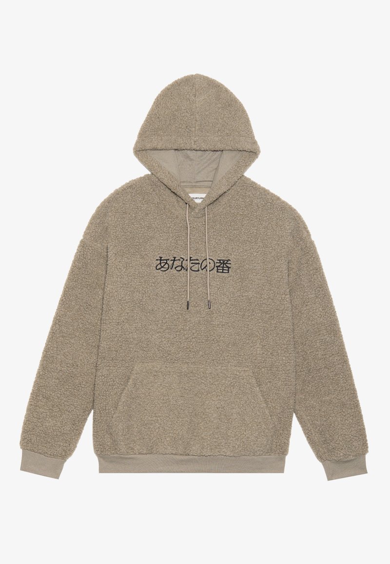 Beige huvtröja, tillverkad av ett texturerat, fluffigt material. Har en kenguruficka och svart japansk text på framsidan.