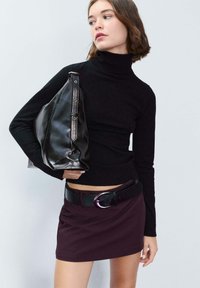 Maglione nero a collo alto con maniche lunghe, abbinato a una gonna bordeaux aderente e a una borsa in pelle nera con accenti metallici.