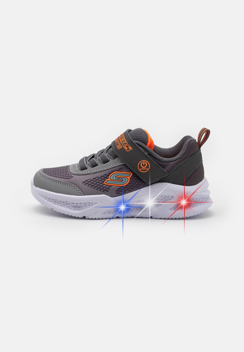 Zapatilla deportiva gris y naranja con parte superior de malla, cuello acolchado, correa ajustable y una suela blanca gruesa con luces.