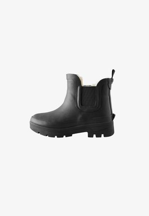 Bottine noire à semelle épaisse, panneau latéral élastique, languettes de traction et doublure en polaire blanche visible à l'ouverture de la cheville.