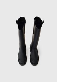Schwarze knöchelhohe Stiefel aus glattem Leder, mit runder Spitze, Gummisohle und Zugschlaufen oben für ein einfaches Anziehen.