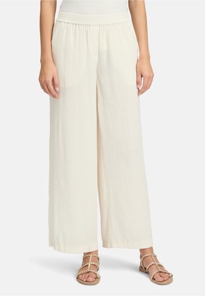 Lässige, cremefarbene Hosen mit weitem Bein aus strukturiertem Stoff und einem elastischen Bund, kombiniert mit flachen Sandalen mit Perlenverzierung.
