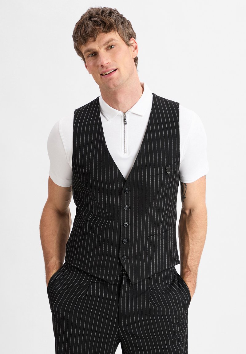 Schwarze Nadelstreifenweste mit tailliertem Design, ausgestattet mit einem Reverskragen, Fronttaschen und sechs Knöpfen. Kombiniert mit einem weißen Kurzarmhemd.