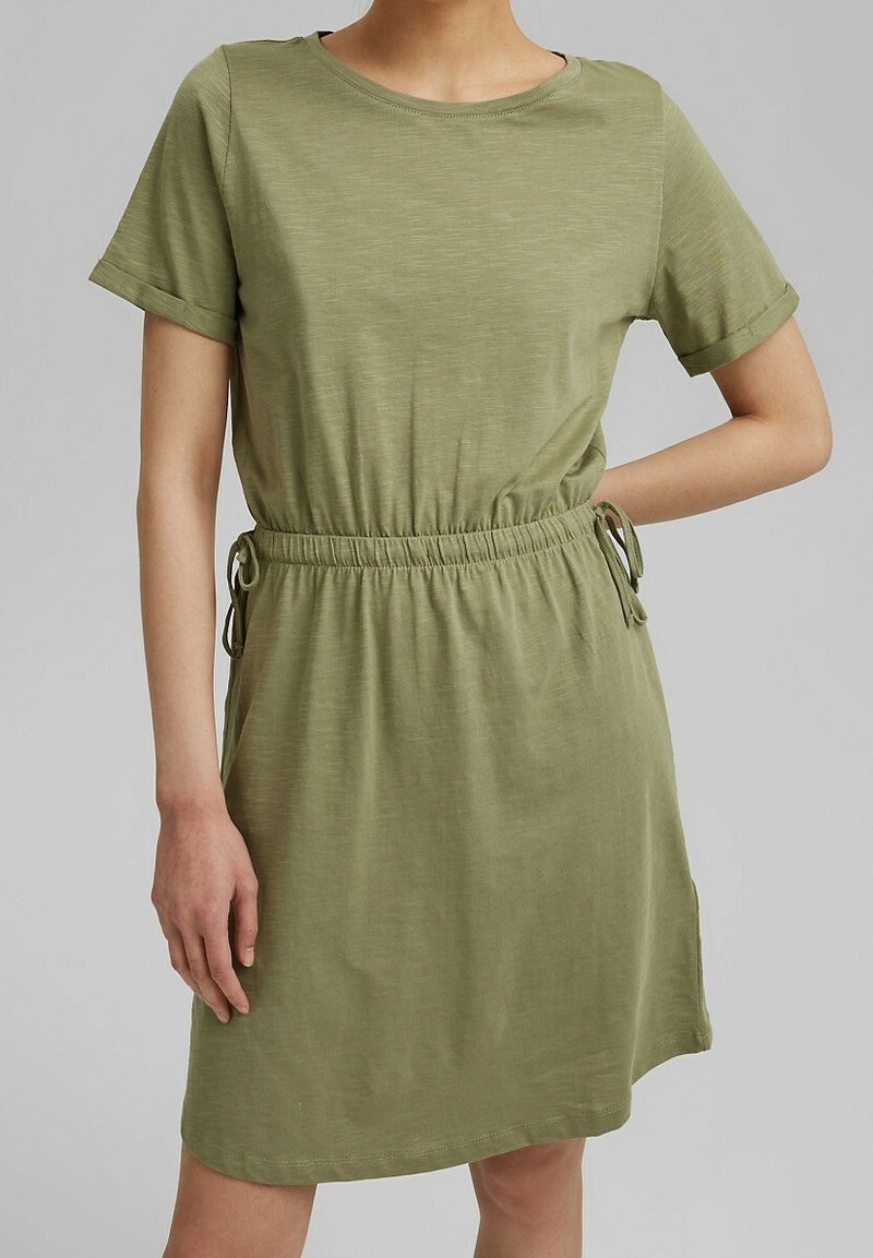 Robe vert olive en tissu doux, avec des manches courtes, un col rond, une taille élastique et des liens sur les côtés ajustables pour un meilleur ajustement.
