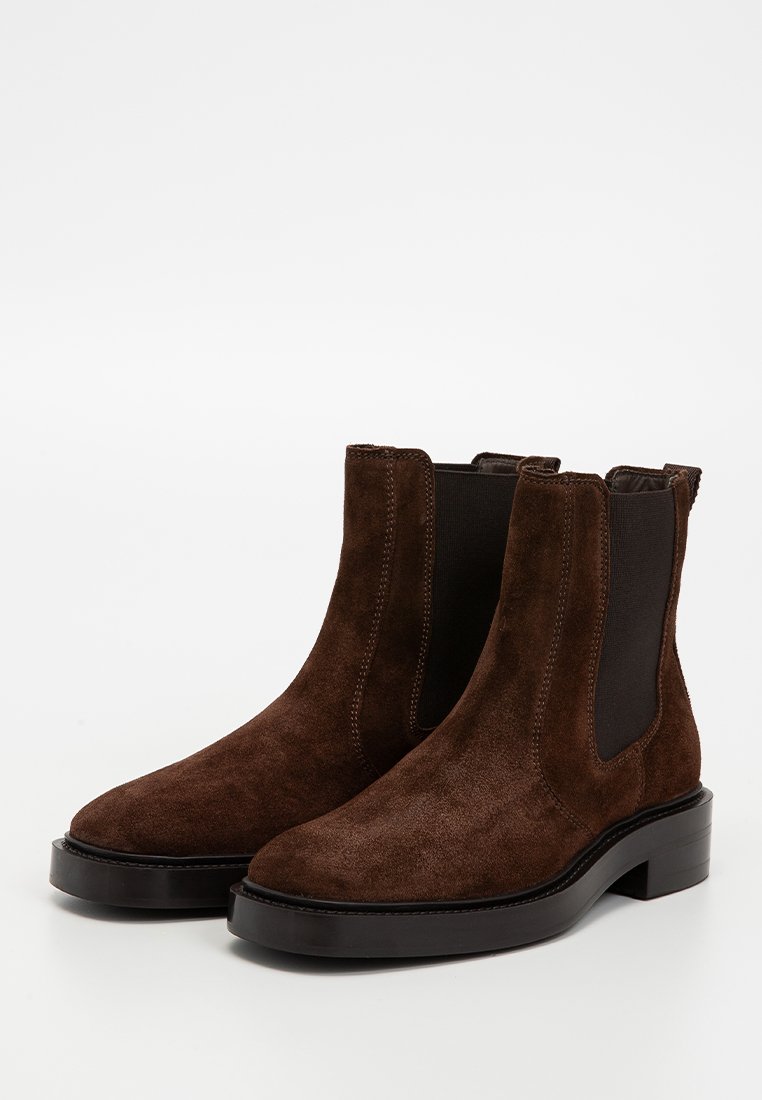 Braune Wildleder-Ankle Boots mit elastischen Seiteneinsätzen, runder Zehenform und dicker schwarzer Sohle. Glatte Textur mit minimalistischem Design.