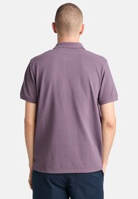 Pánská polokošile s krátkým rukávem světle fialové barvy z bavlny, s klasickým límečkem. Zadní pohled ukazuje hladkou strukturu a minimální detaily šití.