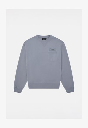 Sudadera gris hecha de una tela suave, con un cuello redondo, mangas largas, puños acanalados y un bolsillo en el pecho con una etiqueta.