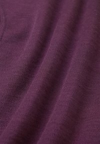 Fioletowa dzianina o miękkiej teksturze, charakteryzująca się gładkim wykończeniem i subtelnymi odcieniami, ukazująca delikatne układanie się oraz rozciągliwość.