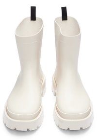 Witte rubberen enkelboots met een gestructureerde afwerking, platte, dikke zolen en zwarte lusjes aan de achterkant. Rond neusstuk, robuuste constructie.