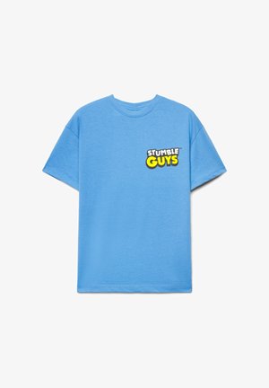 Jasnoniebieska koszulka z krótkim rękawem z logo "STUMBLE GUYS" w białym i żółtym na lewej stronie klatki piersiowej, jednolite tło.