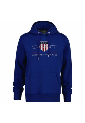 Niebieska bluza z kapturem z kieszenią z przodu, logo "GANT", czerwonobiałą tarczą i napisem "American Sportswear" na piersi.