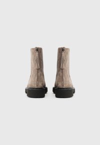 Bottines en suède gris avec une semelle en caoutchouc noir, dotées d'une fermeture éclair arrière et de détails en frange. Texture lisse et design minimaliste.