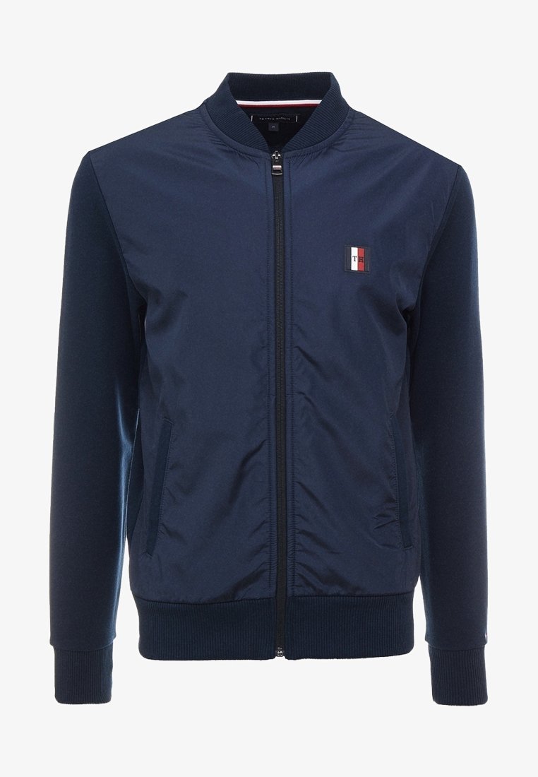 Giacca bomber blu navy con zip, maniche e orlo a costine, caratterizzata da un piccolo logo ricamato e tasche laterali. Tessuto liscio con una vestibilità su misura.