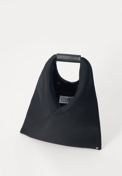 Μαύρη τσάντα από ύφασμα με μοναδικό γωνιακό σχήμα. Διαθέτει λαβή με δερμάτινες λεπτομέρειες και ένα μικρό λογότυπο κοντά στη βάση.