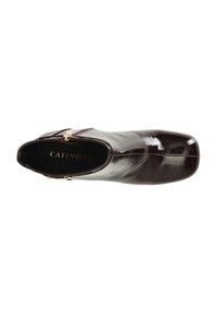 Botín de charol burdeos con un diseño elegante, punta afilada, acentos en hardware dorado y un acabado suave y brillante.