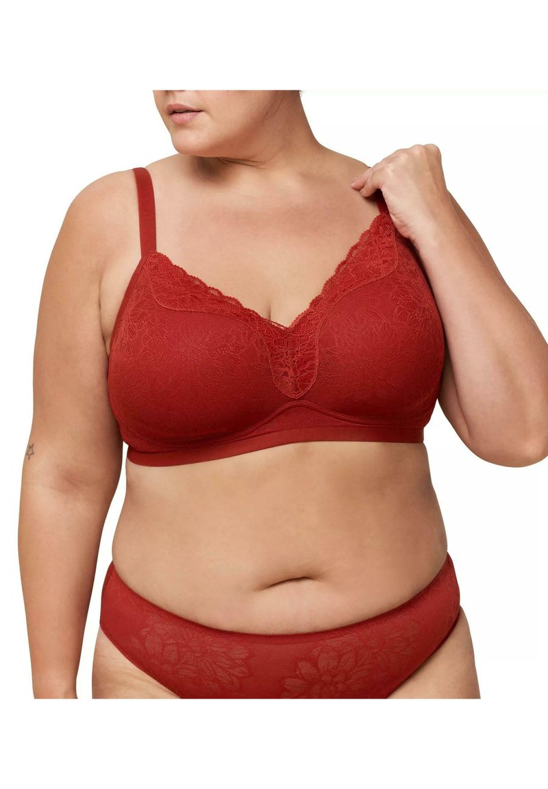 Bralette en dentelle rouge avec motif floral, cups légèrement rembourrées, bretelles ajustables et bande inférieure lisse. Culottes assorties en dentelle rouge visibles en dessous.