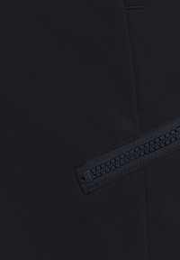 Zwarte stof met een gladde textuur met aan één kant een horizontale ritsdetail. De rits is donker en heeft een geweven patroon.