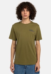 T-shirt en coton vert olive avec un col rond, des manches courtes et "ELEMENT SKATEBOARD CO." imprimé en bleu marine sur le côté gauche de la poitrine.