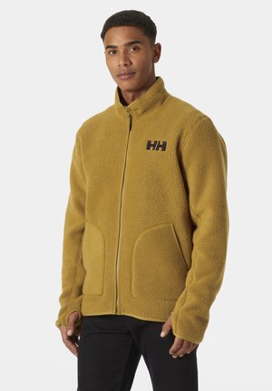 Fleece jacket in mustard yellow with a high collar, zip closure, two front pockets, and logo detailing on the chest. Soft texture.