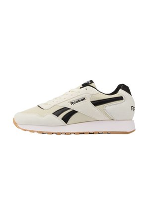 Baskets Reebok blanches et noires avec semelle en gomme, logo latéral, design à lacets et col rembourré sur fond blanc.