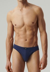 Granatowe męskie slipy bikini wykonane z miękkiego materiału, z szerokim elastycznym paskiem w talii z metką logo oraz gładkimi szwami.