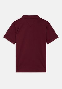 Polo bordeaux à manches courtes, col classique et design avec un dos en V. Matière en coton doux avec une texture lisse.