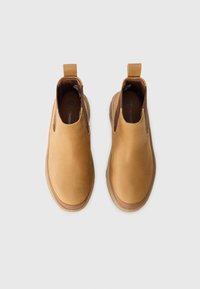 Tan leather ankle boots with elastic side panels, pull tabs, and a thick rubber sole. Smooth texture with a rounded toe design.