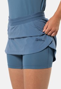 Lichtblauwe sportieve skort over bijpassende shorts, met een brede tailleband en een lichte flounce. Het Jack Wolfskin-logo is zichtbaar op de rand.