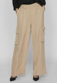 Pantalones cargo de pierna ancha en color beige, confeccionados con un tejido ligero, que cuentan con dos bolsillos laterales y una textura refinada y suave.