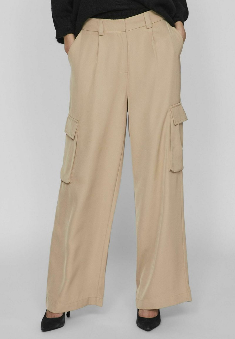 Pantalones cargo de pierna ancha en color beige, confeccionados con un tejido ligero, que cuentan con dos bolsillos laterales y una textura refinada y suave.