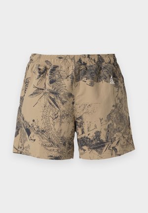 Beige shorts with a black nature print, featuring an elastic waistband and drawstring. Made from lightweight material, suitable for casual wear.