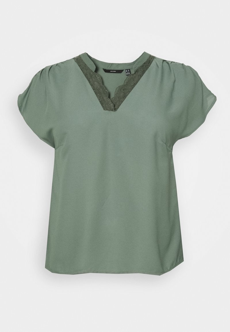 Blouse verte à manches courtes avec un col en V ornée de dentelle. Tissu lisse, coupe décontractée, manches froncées et ourlet droit.