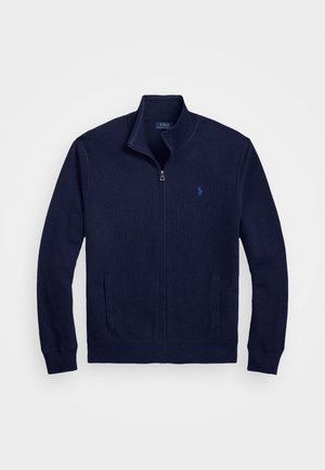 Navy svetr na zip se zvýšeným límcem, vyrobený z textura látky, s dvěma předními kapsami a malým vyšitým logem na hrudi.
