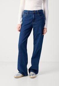 Wide-leg blue denim jeans with a classic five-pocket design and a mid-rise waist, paired with silver sneakers.
