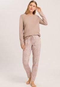Lichtbruin langemouwen shirt gecombineerd met bloemenpatroon, zachte roze pyjamabroek met elastische tailleband en verstelbaar koord.