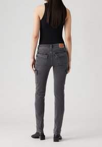 Pantalones cargo de mezclilla gris con corte slim, que cuentan con bolsillos de parche, una etiqueta de cuero con marca en la cinturilla y un diseño de longitud hasta el tobillo.