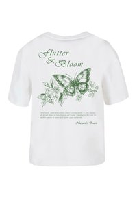 Hvid bomulds T-shirt med et grønt sommerfuglemotiv og blomstermønster på ryggen, med tekst ovenfor og nedenfor designet.