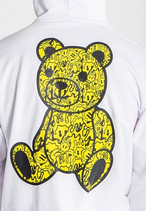 Weißer Kapuzenpullover mit einer großen gelben Teddy-Bären-Grafik auf der Rückseite, versehen mit schwarzen Umrissen und abstrakten Mustern.