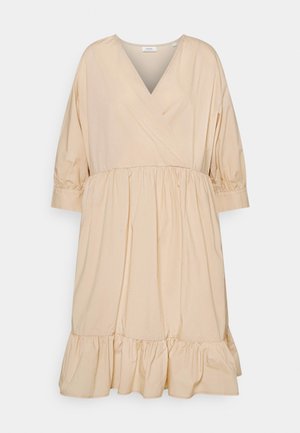 Vestido envolvente de algodón en beige claro, con escote en V, mangas de tres cuartos, cintura fruncida y dobladillo con volantes. Textura suave y diseño fluido.