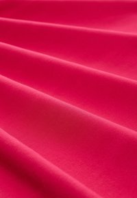 Helles pinkfarbiges Material mit einer glatten Textur zeigt sanfte Falten, die das Licht reflektieren und die weiche Oberfläche sowie die lebendige Farbe betonen.