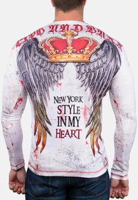 Langarm-T-Shirt mit einem grafischen Design mit einer Krone und Flügeln, in Weiß und Rot mit abgenutzten Mustern, und schwarzem Text, der sagt "NEW YORK STYLE IN MY HEART."