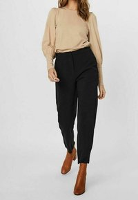 Beige Langarmoberteil mit puffierten Ärmeln, kombiniert mit hoch taillierten schwarzen Hosen und braunen, Absatz-Stiefeletten. Glattes Material und taillierte Passform.