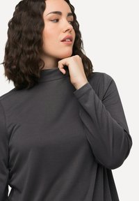 Langärmliges, schiefergraues Rollkragenshirt aus weichem Material, das eine lockere Passform aufweist und eine subtile Textur auf der Oberfläche hat.