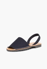 Tummansinisiä mokkanahkaisia slingback-sandaaleja, joissa on teräväkärkinen, avonainen kärki ja teksturoitu kumipohja. Sisältää valkoista ommelta.