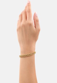 Bracciale in oro con maglie intrecciate, superficie liscia e finitura lucida, indossato su una mano con un tono di pelle neutro.